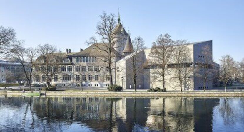 The Swiss National Museum in Zurich overlooking the Limmat river on a clear day.