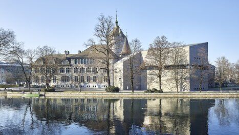 The Swiss National Museum in Zurich overlooking the Limmat river on a clear day.